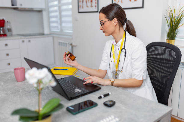 Checking a new type of medicine A young Caucasian female doctor is sitting at her office desk and checking a bottle of pills. Online Suboxone Treatment stock pictures, royalty-free photos & images