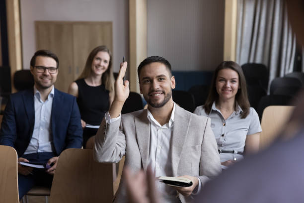 Businessman raises arm, participate in voting during educational training