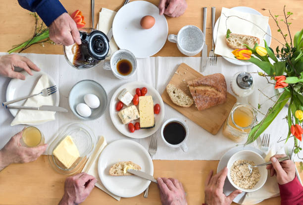 istock Group of people having breakfast together on a wooden table with bread, cheese eggs and coffee, top view from above 1475261376