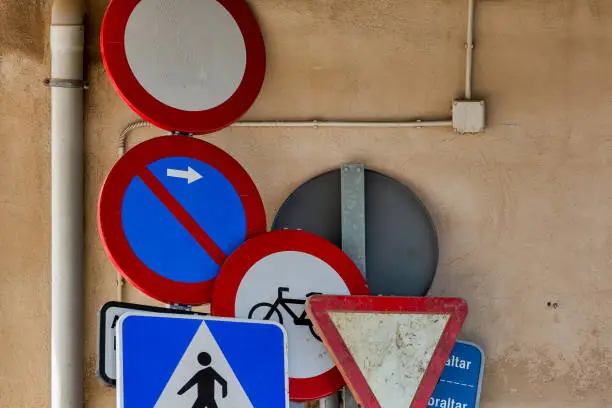 Photo of Used Traffic Signs Leaning on a Wall: Vintage and Rustic Transportation Warning Signs for Urban Decay and Recycling Themes