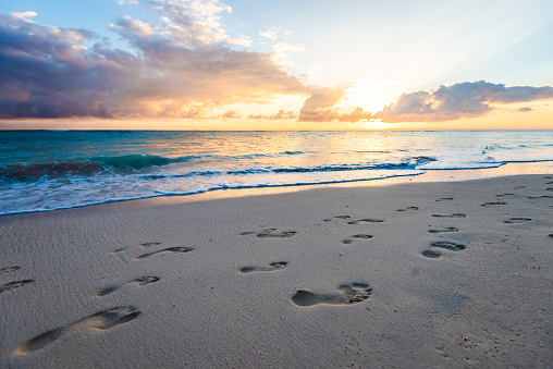 Beautiful sunrise at the ocean. There are footprints on the sand