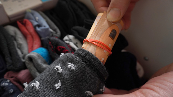 hand takes out money from twisted socks lying in the closet. savings for a rainy day