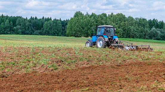 Minsk region - July 20, 2018: A tractor plows a field, pulling a plow. Agricultural work