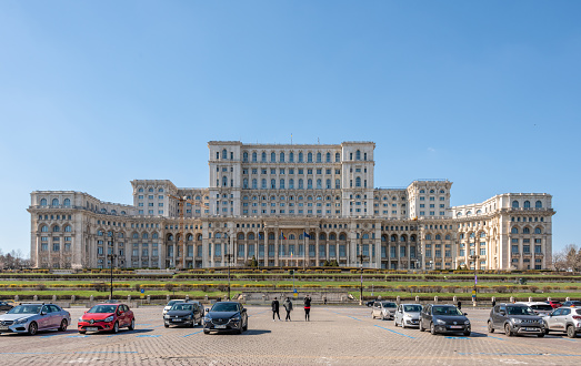 Bucharest, Romania. March 13, 2023: The imposing front of the Romanian Parliament Building in Bucharest, with car park.