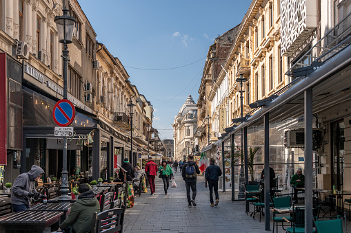 Bucharest, Romania. March 13, 2023: Tourists walking in old town Bucharest with street cafes.
