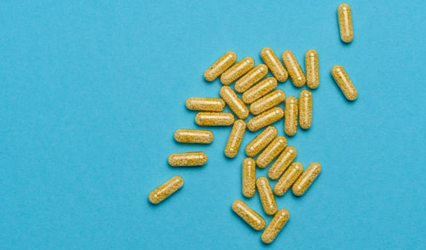 istock Transparent medical capsules with yellow granules inside on a blue background, tablets for treatment, vitamins 1475266517