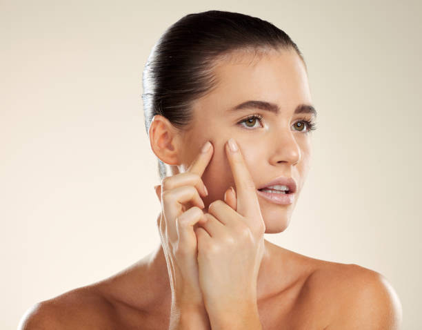 istock Face, hands and blackhead with a woman checking or examining her skin for acne problems in studio. Facial, fingers and breakout with an attractive young female indoor to squeeze or pop a pimple 1475266956