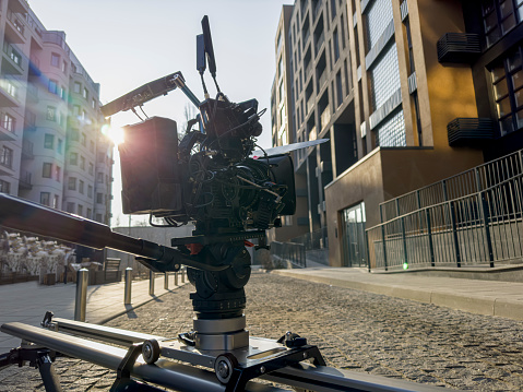 movie camera on the slider in the backlight from the sun, the rays of the sun. shooting outdoors in an urban location
