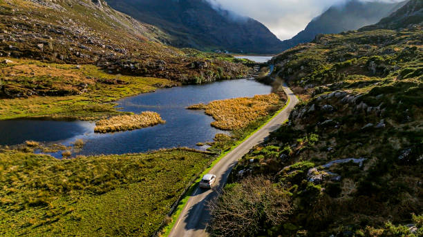 gap de dunloe, comté de kerry, voiture sur la route de montagne au bord du lac, vue aérienne d’un col de montagne pittoresque, vue aérienne de la nature et vue de la route, vue aérienne de la route sinueuse, vidéo de relaxation de la nature, conduit - lanneau de kerry photos et images de collection