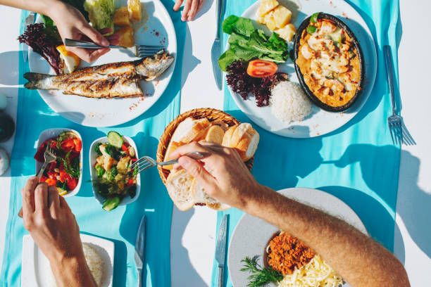 Top view of dinner table with fish, salad, bread, spaghetti and chicken
