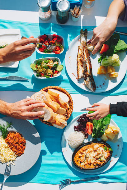top view of dinner table with fish, salad, bread, spaghetti and chicken - akdeniz mutfağı stok fotoğraflar ve resimler