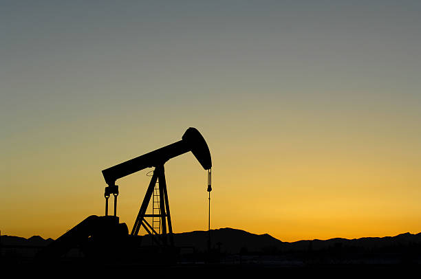 Oil and Gas Industry Oil and Gas Industry Crude Oil Pump silhouetted against a mountain sunset with Copy Space goldco prices stock pictures, royalty-free photos & images