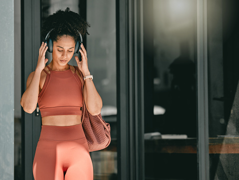 Fitness, walking and black woman listen to music, relax podcast or radio for calm, stress relief or wellness mockup. Headphones, leaving gym and mock up girl on travel after training workout exercise