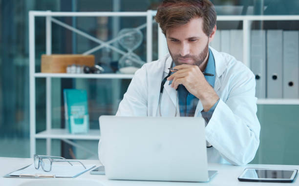 istock Doctor, scientist and laptop with a man reading and thinking while doing medical research on database or data analysis at desk. Healthcare worker with technology for internet. search and innovation 1475273533