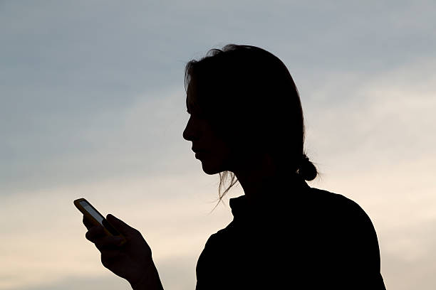 istock silhouette woman cellphone PDA text message sky 147527405
