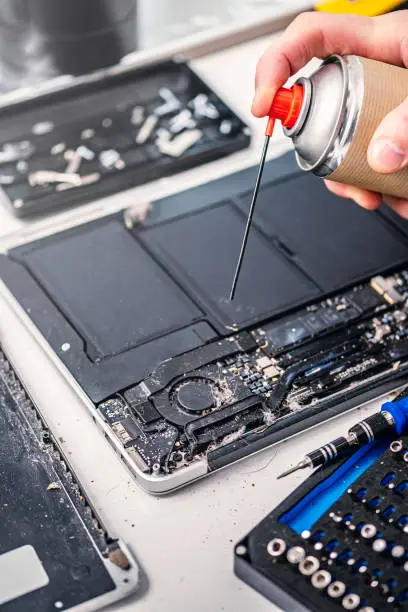 Close-up of a technician fixing a modern laptop computer. Ideal for illustrating the “right to repair” movement. Colour, vertical format with some copy space.