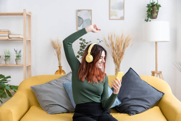 istock Cheerful woman in headphones on sofa 1475275228