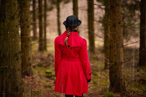 Outdoors portrait of woman in red. Standing in the rain outdoors in forest