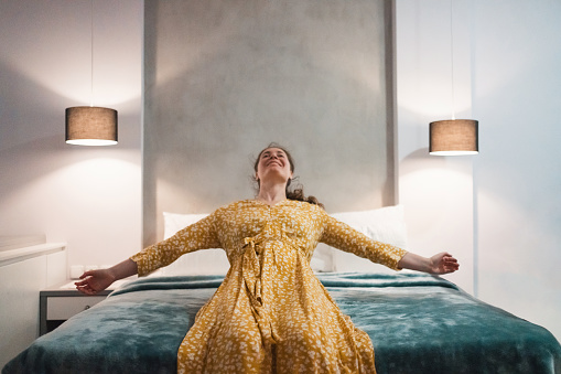 Woman jumping on a hotel bed
