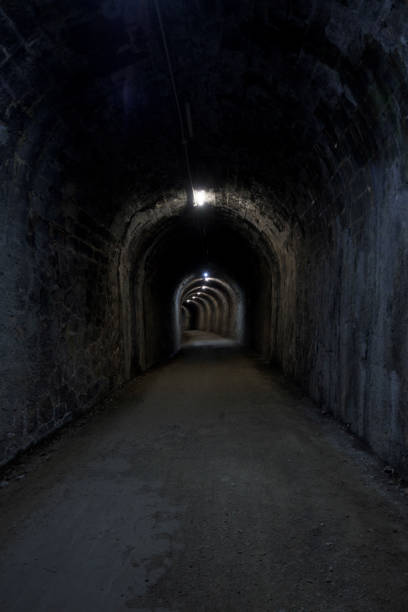 istock stone tunnel dark wet old curved stone illuminated with dirt floor 1475278605