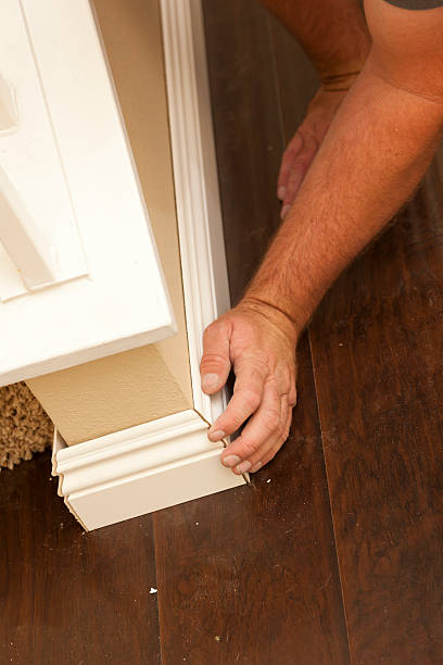 istock Contractor Fitting New Baseboard to Wall and Laminate Flooring 147527884