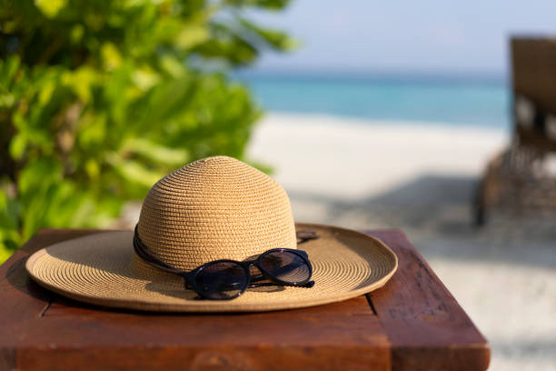 Straw hat and sunglasses on the beach. Beach holiday concept.