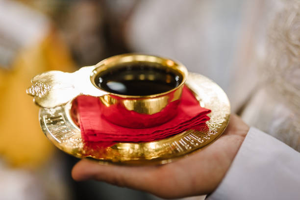 cuenco de bodas en la iglesia en la mano del sacerdote. copa de oro de sangre. un cáliz de vino de comunión. cerrar. divina liturgia. detalles de la ceremonia de boda en la iglesia. - communion altar last supper wedding fotografías e imágenes de stock