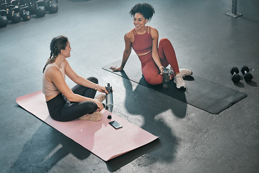 Fitness, relax or friends in gym talking, conversation or speaking of body goals after workout exercises. Girls, gossip or healthy sports women resting or relaxing on break after training together