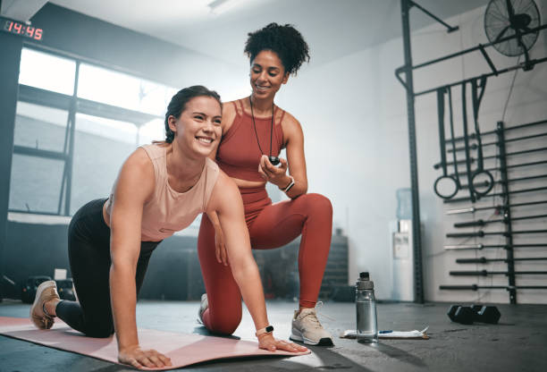 personal trainer, esercizio fisico e cronometro con una donna di colore che allena un cliente in una palestra durante il suo allenamento. salute, fitness o allenamento e un'atleta pronta a plank con un allenatore che registra il tempo - endurance sport foto e immagini stock