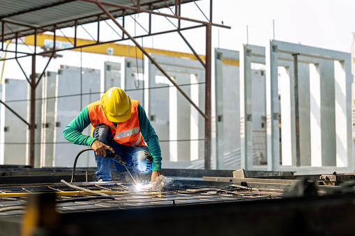 Workers at a construction site weld metal structures of precast concrete slabs.