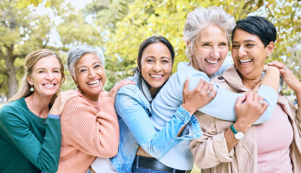 amigos, parque y grupo de mujeres se abrazan disfrutando de la unión, el tiempo de calidad y relajarse juntas en la naturaleza. diversidad, amistad y retrato de mujeres mayores felices con sonrisa, abrazo y paz al aire libre - 50 days old fotografías e imágenes de stock