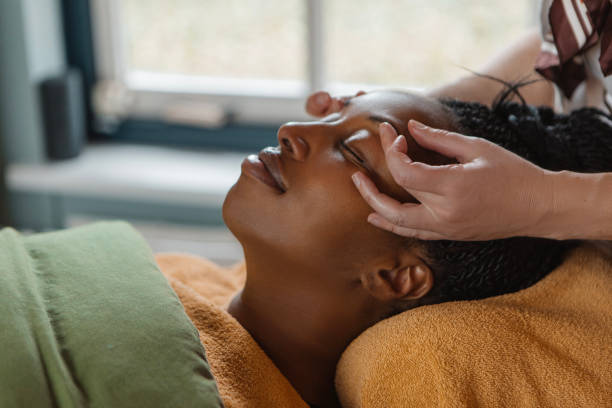 massage facial par une femme professionnelle pour une belle femme noire - esthéticienne photos et images de collection