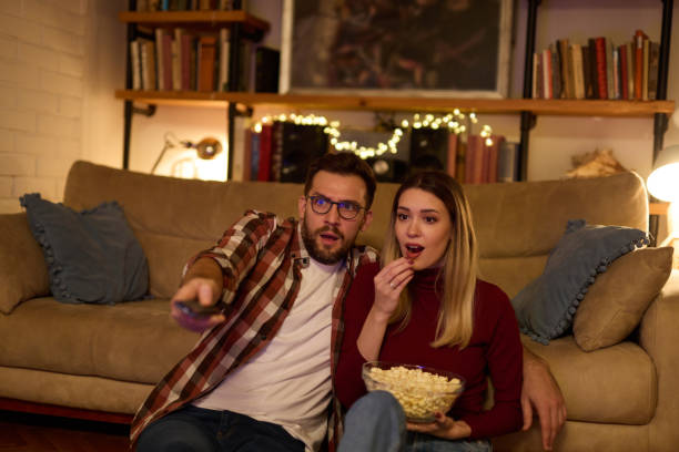 istock Young romantic couple watching TV at home 1475289894