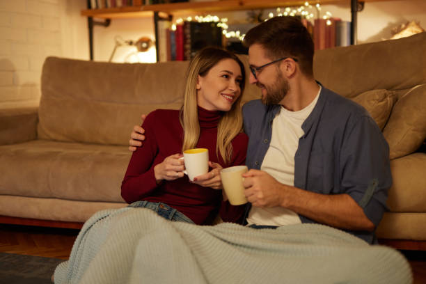 istock Young couple drinking tea while sitting in the living room at night 1475289991