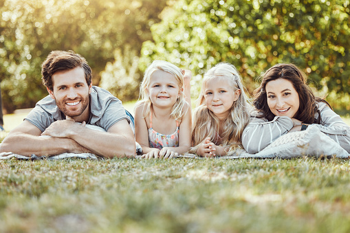 Family, park and portrait of parents and children outdoor on garden grass with love and smile. Happy, nature and kids with mom and dad together on vacation with parent care and fun relax on a picnic