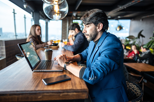 Mature businessman using laptop in the restaurant on the rooftop