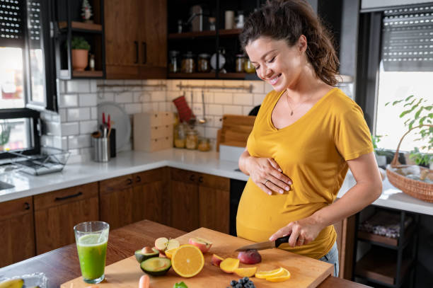 istock Young beautiful pregnant lady making various fruit smoothies in the home kitchen 1475300308