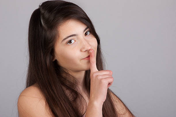istock happy young woman holds finger on her lips, silent please 147530585