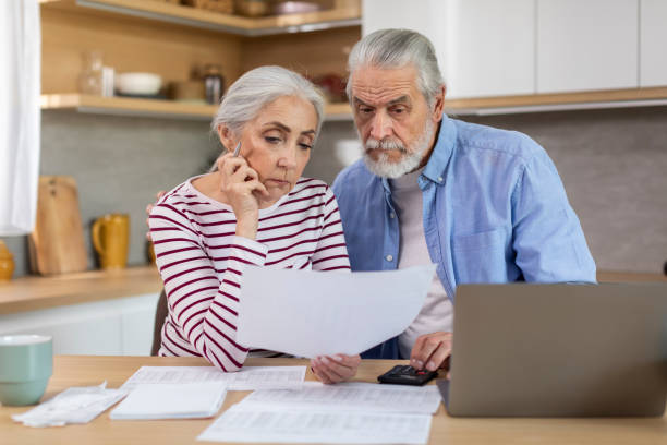 upset elderly couple checking financial documents while calculating family budget at home - two parent family indoors home interior domestic kitchen imagens e fotografias de stock