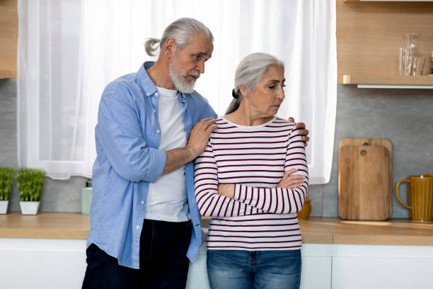 caring senior man comforting his offended wife in kitchen at home - two parent family indoors home interior domestic kitchen imagens e fotografias de stock