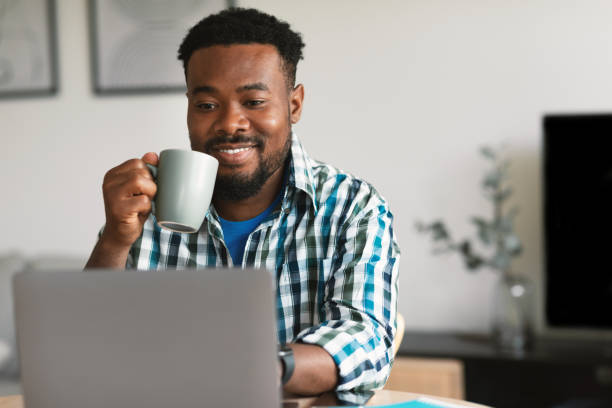 istock African American Male Using Laptop Drinking Coffee Working Online Indoor 1475307189