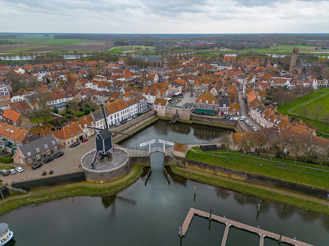 This picture was taken by a drone. It shows the small village center of Heusden, a village in Noord-Brabant. You can see a small harbour with an old bridge, some typical Dutch houses and a windmill.