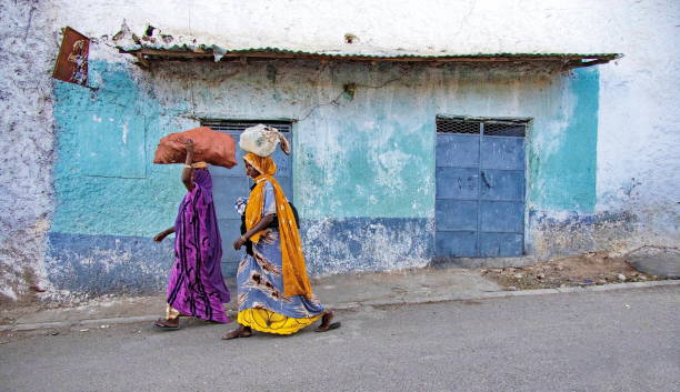 Women walking at the streets of Harar old town (Harar Jugol), carrying stuff on their heads, Ethiopia Harar, Ethiopia - January 12, 2023: Women walking at the streets of Harar carrying stuff on their heads. Harar (or Harrar or Harer) is a city in Ethiopia, located on a hilltop at 1885 meters. Carrying on the head is common in many parts of the developing world, ethiopia city stock pictures, royalty-free photos & images