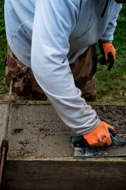 istock Bricklayer spreading concrete with a trowel and level to build a wall at a construction site 1475310764