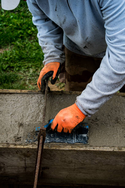 istock Bricklayer spreading concrete with a trowel and level to build a wall at a construction site 1475310767