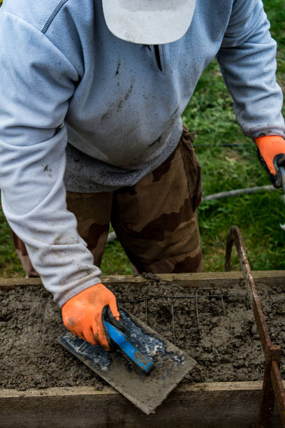 istock Bricklayer spreading concrete with a trowel and level to build a wall at a construction site 1475310827