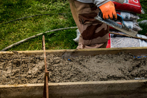 istock Bricklayer spreading concrete with a trowel and level to build a wall at a construction site 1475310889