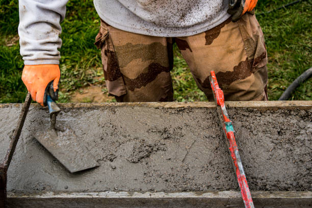 istock Bricklayer spreading concrete with a trowel and level to build a wall at a construction site 1475310893