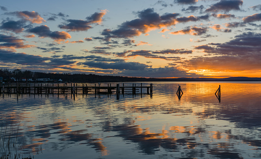 Wooden chair on beach of relaxing lake at sunset