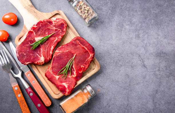 bife de carne fresca em um fundo de concreto - rib eye steak beef cutting board meat - fotografias e filmes do acervo